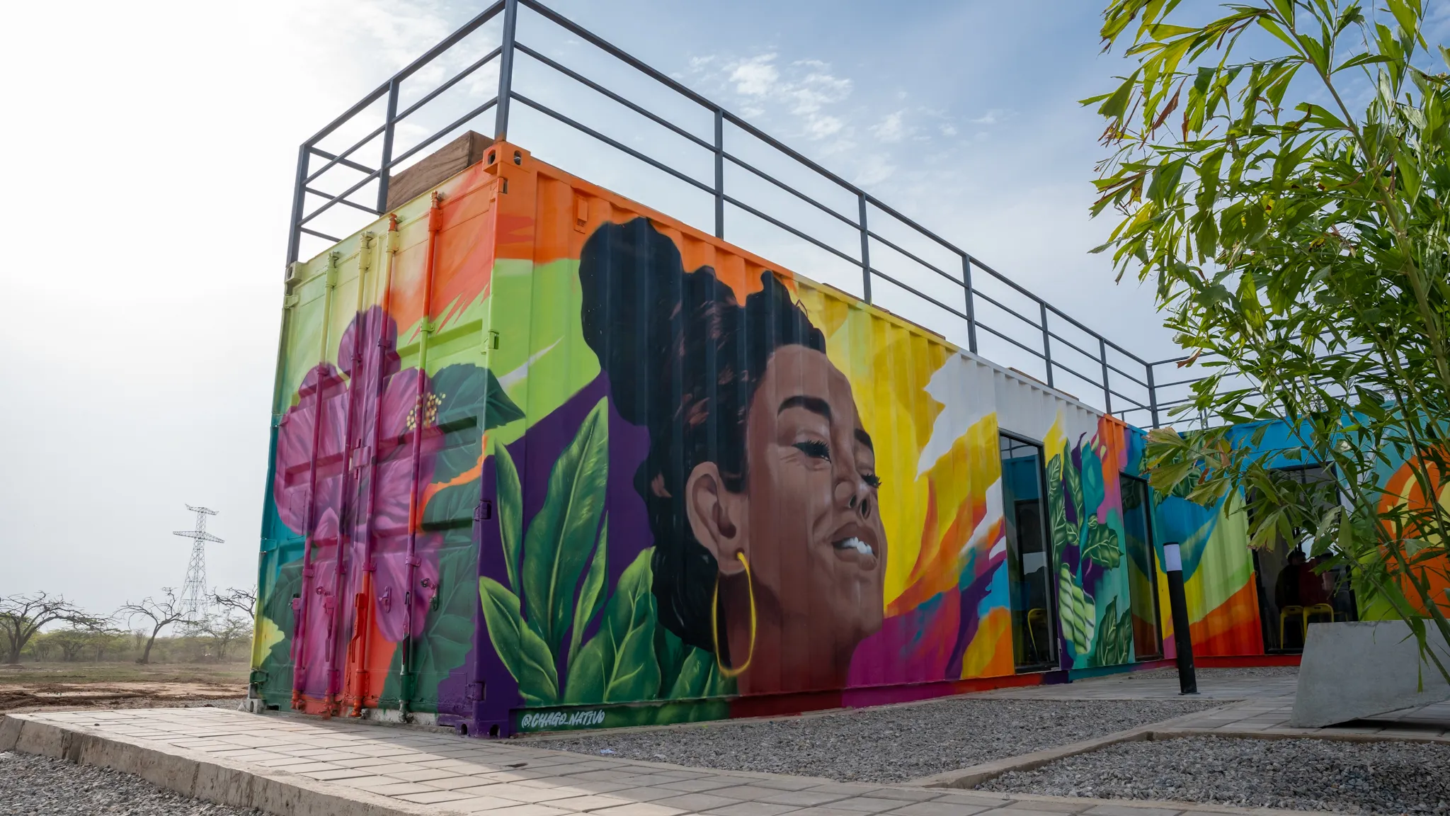 Mural colorido con el rostro de una mujer afrodescendiente pintado sobre contenedores marítimos.